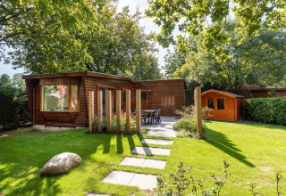 Træchalet og have med udendørs spiseplads i solskin ved Bungalowpark Het Verscholen Dorp, Holland.