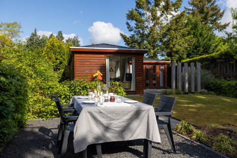 Buitentafel gedekt bij een tiny house op Bungalowpark Het Verscholen Dorp in Nederland voor een tuinmaaltijd.