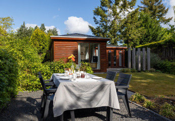 Udendørs spisning ved et bord i haven foran et lille træhus på Bungalowpark Het Verscholen Dorp, Holland.