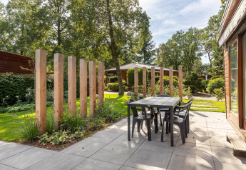 Terrasse extérieure du Cozy Chalet à Bungalowpark Het Verscholen Dorp, avec table, chaises et poteaux en bois.