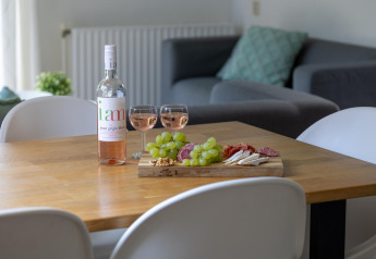 Wine and tapas on wooden table inside Cozy Chalet at Bungalowpark Het Verscholen Dorp, Netherlands.