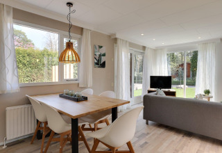 Helles Wohnzimmer im Cozy Chalet, Bungalowpark Het Verscholen Dorp, mit Esstisch und Gartenblick.