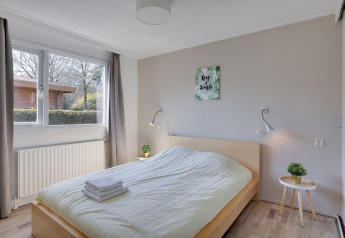 Chambre lumineuse du Cozy Chalet au Bungalowpark Het Verscholen Dorp, Pays-Bas, avec grande fenêtre et déco.