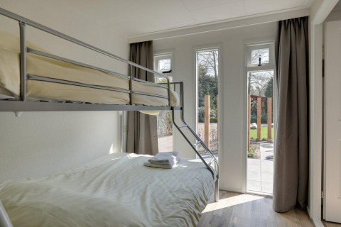 Stanza luminosa con letto a castello e grandi finestre al Cozy Chalet, Bungalowpark Het Verscholen Dorp, Paesi Bassi.