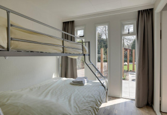 Helles Zimmer mit Etagenbett und großen Fenstern im Cozy Chalet, Bungalowpark Het Verscholen Dorp, Niederlande.