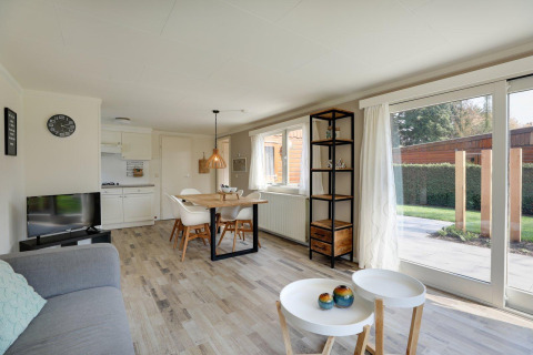 Lichte, moderne leefruimte in Cozy Chalet in Bungalowpark Het Verscholen Dorp met grote ramen en eethoek.