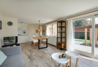 Lichte, moderne leefruimte in Cozy Chalet in Bungalowpark Het Verscholen Dorp met grote ramen en eethoek.