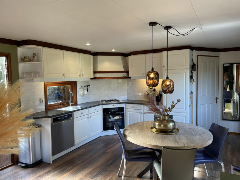 Moderne compacte keuken en eetplaats met ronde tafel, hanglampen en houten accenten in een Vlaamse tiny house.