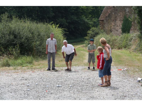 Una familia juega a la petanca al aire libre en Feather Down La Ferme de Penquelen Huella, Bretaña, Francia.