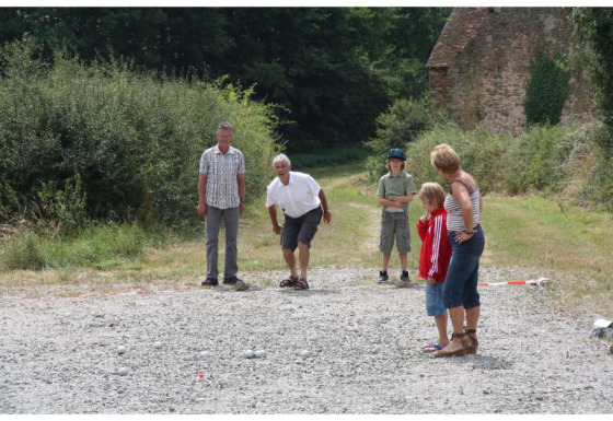 Una familia juega a la petanca al aire libre en Feather Down La Ferme de Penquelen Huella, Bretaña, Francia.