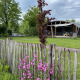 Lodge esterna al Holiday Park 't Rheezerwold nei Paesi Bassi con staccionata e fiori vivaci in giardino.