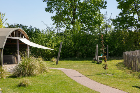 Udsigt over Outdoor Lodge med overdækket terrasse og grønne omgivelser i Holiday Park 't Rheezerwold, Holland.