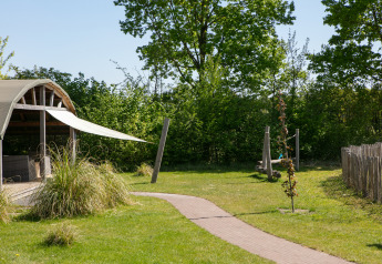 Buitenlodge met overdekt terras en groene omgeving in Vakantiepark 't Rheezerwold in Nederland.