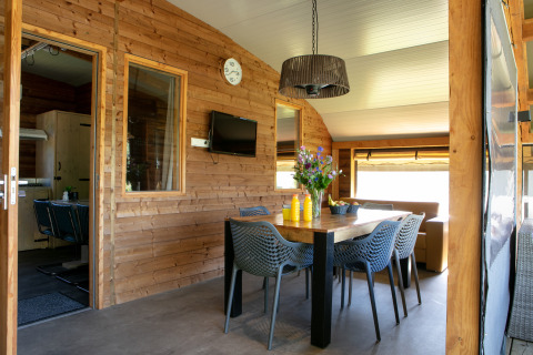 Indoor dining area of Outdoor Lodge at Holiday Park 't Rheezerwold, Netherlands, with wooden walls and decor.