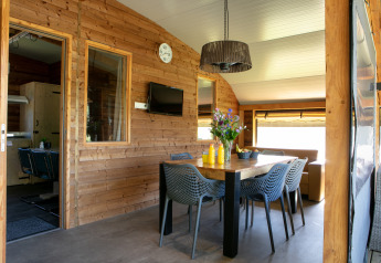Indendørs spiseområde i Outdoor lodge på Holiday Park 't Rheezerwold med trævægge og moderne møbler.