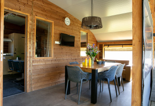 Eethoek binnen in de Outdoor lodge van Holiday Park 't Rheezerwold met houten wanden en eigentijds meubilair.