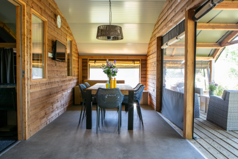 Interior de madera de la Outdoor lodge con mesa de comedor en Holiday Park 't Rheezerwold, Países Bajos.