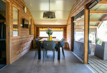 Holzinterieur einer Outdoor Lodge mit Esstisch und Stühlen im Holiday Park 't Rheezerwold, Niederlande.