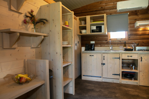 Hyggeligt køkken i Outdoor Lodge på Holiday Park 't Rheezerwold i Holland med træfinish og åbne hylder.