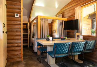 Interiør af hyggelig Outdoor lodge med spisebord, blå stole og trævægge i Holiday Park 't Rheezerwold.