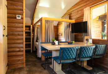 Cozy interior of an Outdoor lodge at Holiday Park 't Rheezerwold with dining table, blue chairs, and wood walls.