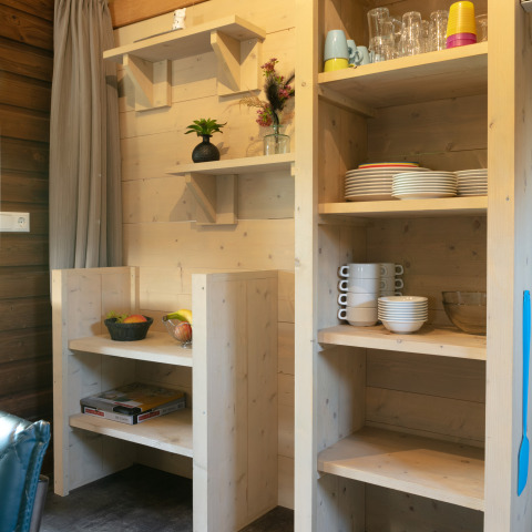 Étagères de cuisine dans un lodge extérieur avec vaisselle et corbeilles de fruits à Holiday Park 't Rheezerwold, Pays-Bas.