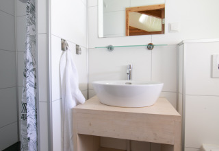 Moderne badkamer met ronde waskom, spiegel, handdoek en houten wastafel in Outdoor Lodge in Nederland.