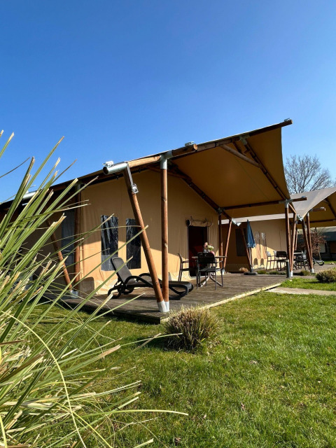 Luxuriöses Safarizelt mit Terrasse im Ferienpark 't Rheezerwold in den Niederlanden bei sonnigem Wetter.