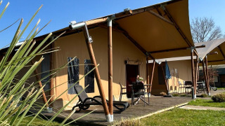 Luxe safaritent lodge met terras bij Vakantiepark 't Rheezerwold in Nederland op een zonnige dag.