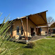 Luxe safaritent lodge met terras bij Holiday Park 't Rheezerwold in Nederland onder een blauwe lucht.
