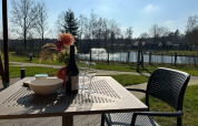 Vista desde una tienda de lujo en Holiday Park 't Rheezerwold, Países Bajos, con vino y flores en la mesa.