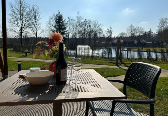 Uitzicht vanuit een luxe safaritent op Vakantiepark 't Rheezerwold in Nederland, wijn en bloemen op tafel.