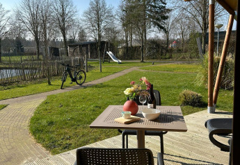 Udsigt fra en terrasse ved en luksustelt lodge i Holiday Park 't Rheezerwold, Holland, med have og legeplads.
