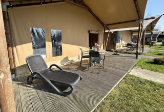 Luxuriöses Safarizelt mit Terrasse, Liegestuhl und Gartenmöbeln im Ferienpark 't Rheezerwold in den Niederlanden.