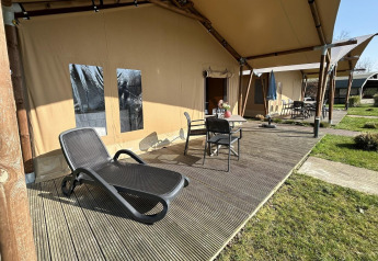 Luxuriöses Safarizelt mit Terrasse, Liegestuhl und Gartenmöbeln im Ferienpark 't Rheezerwold in den Niederlanden.