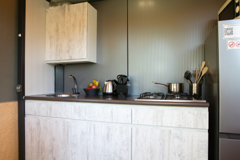 Moderne Kochnische mit Spüle, Herd, Kühlschrank und Obstkorb in einer Luxuszeltlodge in den Niederlanden.
