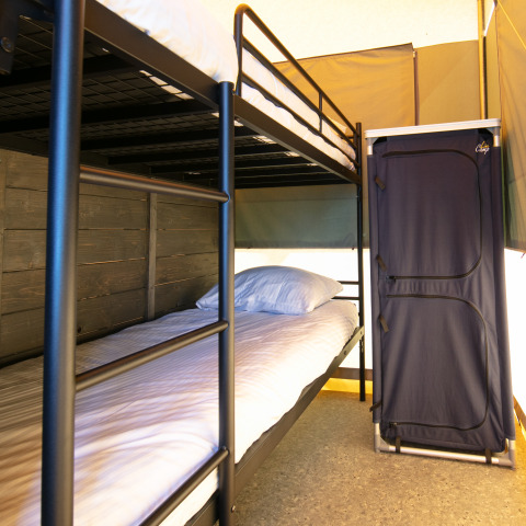 Interieur van een luxe safaritent met stapelbedden en kast op Vakantiepark 't Rheezerwold in Nederland.