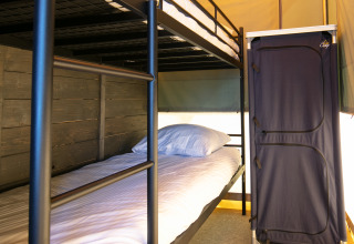 Interieur van een luxe safaritent met stapelbedden en kast op Vakantiepark 't Rheezerwold in Nederland.