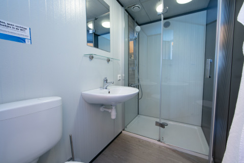 Salle de bain avec douche, lavabo, miroir et toilettes dans la Luxury Tent Lodge du Holiday Park 't Rheezerwold.