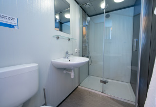 Badezimmer mit Dusche, Waschbecken, Spiegel und WC im Luxury Tent Lodge im Holiday Park 't Rheezerwold.