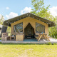 Tienda safari en Camping De Betteld, Países Bajos, con terraza de madera, banco y mesa de picnic al aire libre.