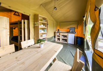 Interno di una tenda safari al Camping De Betteld nei Paesi Bassi con cucina, tavolo e letti a castello.