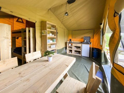 Interno di una tenda safari al Camping De Betteld nei Paesi Bassi con cucina, tavolo e letti a castello.
