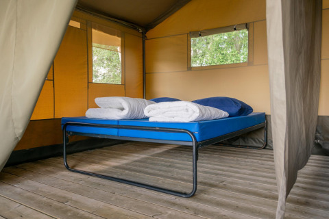 Intérieur d'une tente safari avec lit sur plancher en bois au Camping De Betteld, aux Pays-Bas.