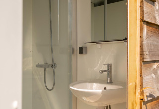 Salle de bain avec douche et lavabo dans une tente safari au Camping De Betteld, Pays-Bas, vue intérieure.