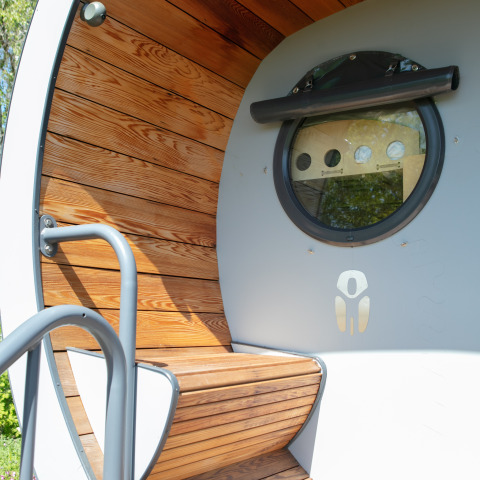 Entrada de la tiny house Anthropod con paneles de madera y ventana redonda en Holiday Park 't Rheezerwold, Países Bajos.