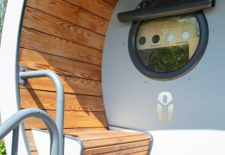 Indgangsparti til tiny house Anthropod med træpaneler og rundt vindue i Holiday Park 't Rheezerwold, Holland.