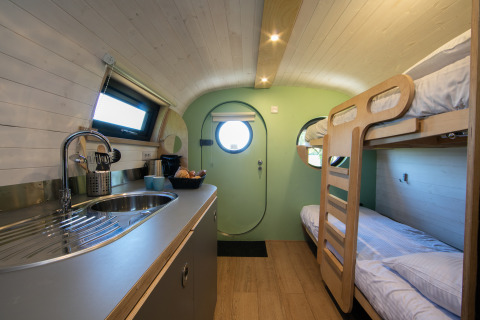 Interieur van de Anthropod tiny house met keuken en stapelbedden in Holiday Park 't Rheezerwold, Nederland.