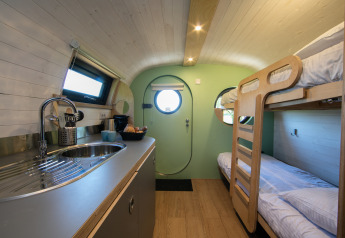 Interieur van de Anthropod tiny house met keuken en stapelbedden bij Holiday Park 't Rheezerwold, Nederland.