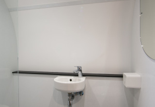 Baño moderno y minimalista de una tiny house en Holiday Park 't Rheezerwold, Países Bajos, con lavabo y espejo.